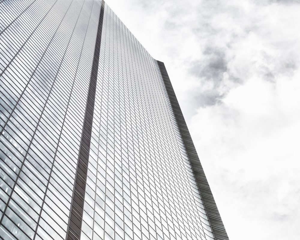 A low angle shot of a modern glass skyscraper on a cloudy sky background